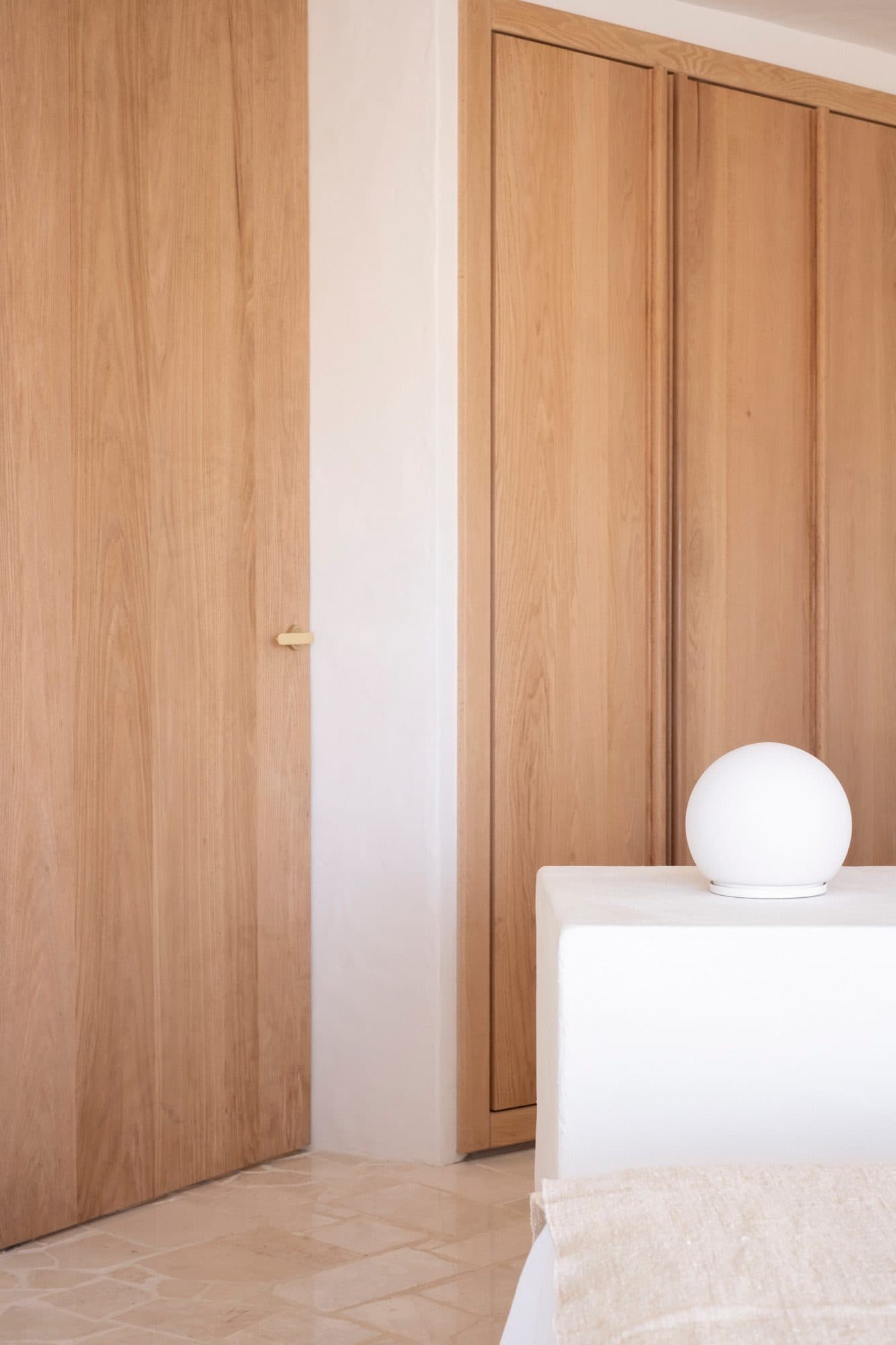Pale timber doors above a plaster ledge holding white ceramic vases.